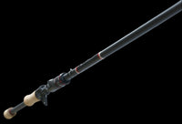 The Doozie Series 72 MH X-Ray Precision Power Heavy Cover Rod by Keeper Rods-Doozie is a black fishing rod with red accents and a cork handle, highlighted against a black background. Its sleek design features multiple eyelets, making it perfect for bass fishing enthusiasts.